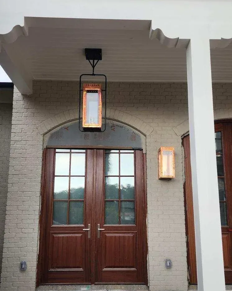 Copper gas lanterns beside a mahogany double-door entry